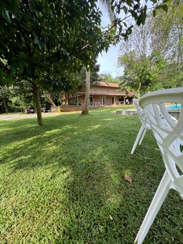 a white chair sitting on the grass in a yard at Theeram Riverside Holiday Home in Māla