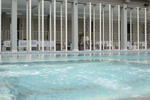 a swimming pool with blue water and white chairs at Navela Hotel & Convention in Ratchaburi