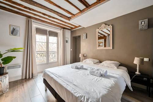 une chambre avec un grand lit et une grande fenêtre dans l'établissement Grand 2 pieces typique du Marais - FLAT-GUEST, à Paris