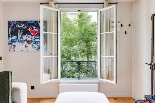 - une fenêtre ouverte dans une chambre avec un canapé blanc dans l'établissement Bel appartement 2 pièces place de la République 75011, à Paris