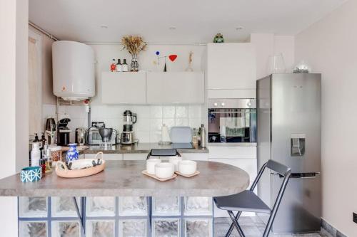 une cuisine avec des armoires blanches et une table et des chaises dans l'établissement Bel appartement 2 pièces place de la République 75011, à Paris