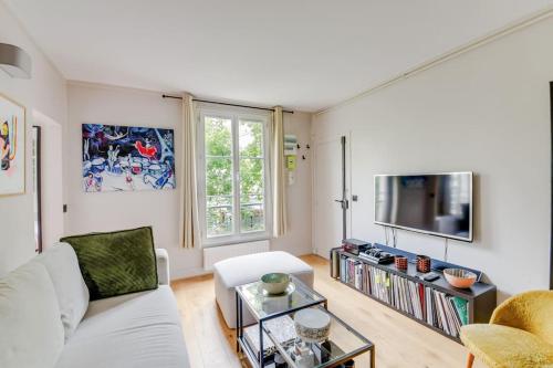 un salon avec un canapé blanc et une télévision dans l'établissement Bel appartement 2 pièces place de la République 75011, à Paris
