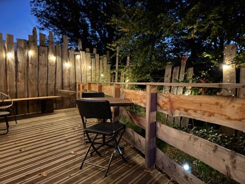 a table and chairs on a deck with a fence at Domaine des Constellations - Tiny Houses & Bains Nordiques in Orbey
