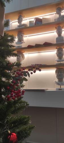 a christmas tree in front of a shelf with books at L Suites The Writer's House in Gythio