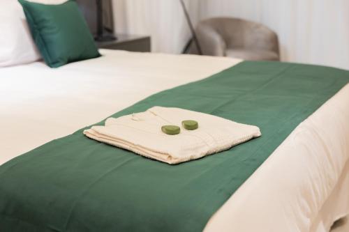 a towel on a bed with two green pills on it at Hotel Boutique Gualamba in General Pinedo