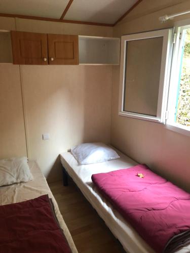 une petite chambre avec deux lits et une fenêtre dans l'établissement Les Chalets Du Moulin Du Châtain 2, à Payzac