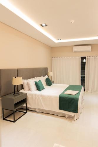 a bedroom with a large white bed with green pillows at Hotel Boutique Gualamba in General Pinedo