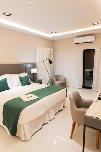 a bedroom with a large bed and a chair at Hotel Boutique Gualamba in General Pinedo