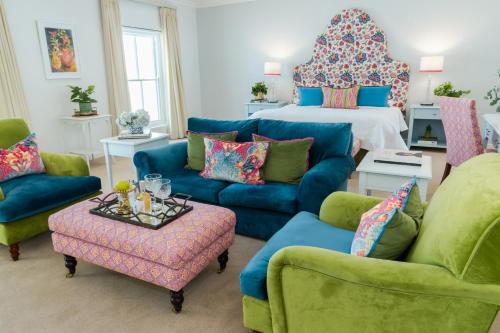 a living room with a bed and a blue couch and chairs at Last Word Franschhoek in Franschhoek