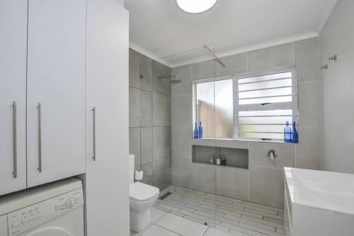 a white bathroom with a toilet and a sink at Pet friendly & Close to Beach at 2 Saasveld in Bloubergstrand