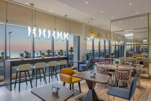 a restaurant with tables and chairs and a view of the ocean at Hampton By Hilton Kuwait Salmiya in Kuwait