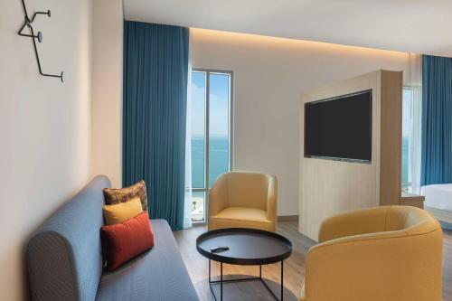 a hotel room with a couch and chairs and a television at Hampton By Hilton Kuwait Salmiya in Kuwait