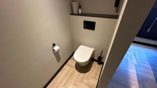 a white toilet in a bathroom with a wooden floor at Boutique Hotel Le Faucon in Valkenburg