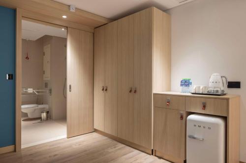 a kitchen with wooden cabinets and a bathroom with a toilet at Hampton By Hilton Kuwait Salmiya in Kuwait