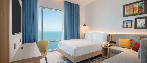 a hotel room with a bed and a large window at Hampton By Hilton Kuwait Salmiya in Kuwait