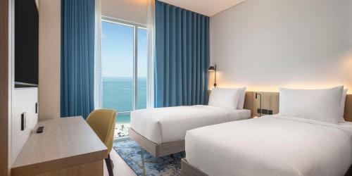 a hotel room with two beds and a window at Hampton By Hilton Kuwait Salmiya in Kuwait