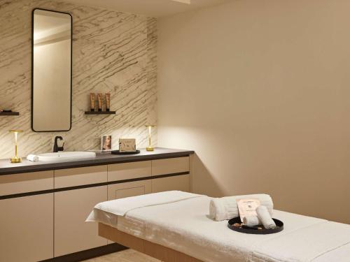 a bathroom with a bed and a sink and a mirror at Domaine du Liziec Vannes - MGallery Collection in Vannes
