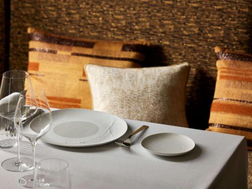 a table with white plates and wine glasses on it at Domaine du Liziec Vannes - MGallery Collection in Vannes