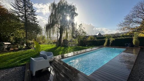 a swimming pool in a yard with two white chairs at Boutique Hotel Le Faucon in Valkenburg