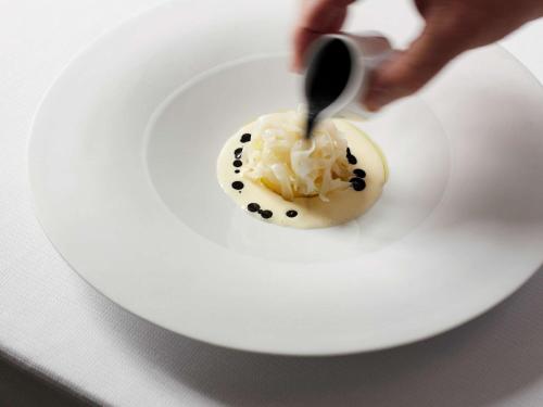 a person eating a dessert on a plate with a spoon at Domaine du Liziec Vannes - MGallery Collection in Vannes