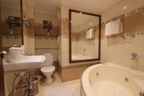 a bathroom with a tub and a toilet and a sink at Regenta Orko's Haridwar, Motichur, 10 min from Har ki Pauri in Haridwār