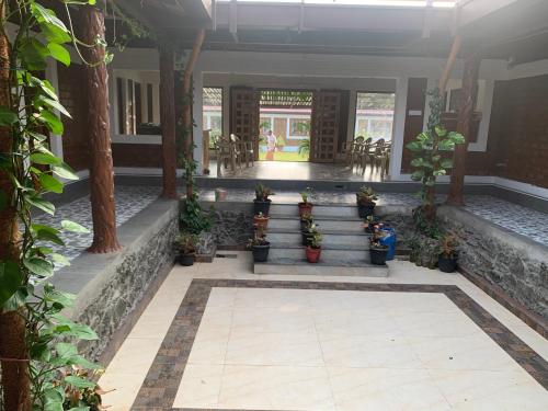 a lobby with stairs and potted plants and tables at Love Green Resorts in Palladam