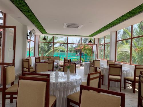 a dining room with a table and chairs and windows at Love Green Resorts in Palladam