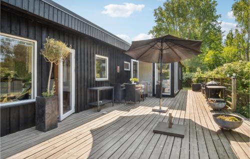 a wooden deck with an umbrella on a building at Cozy Home In Kalundborg With Wifi in Kalundborg