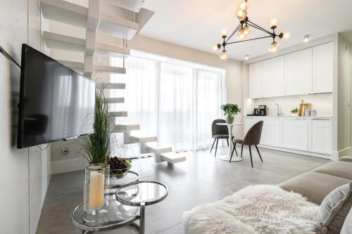 a living room with a couch and a tv and a kitchen at ApartPark by Baltic Home in Świnoujście