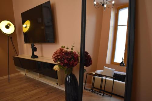 un salon avec une télévision et un vase fleuri dans l'établissement La République d'Emmanuel, à Carcassonne