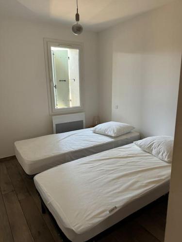 deux lits jumeaux dans une chambre avec fenêtre dans l'établissement Appartement bastide à la campagne, à Mimet