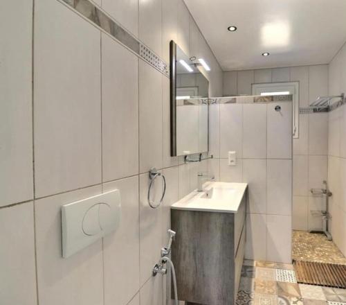une salle de bain blanche avec un lavabo et un miroir dans l'établissement Appartement bastide à la campagne, à Mimet