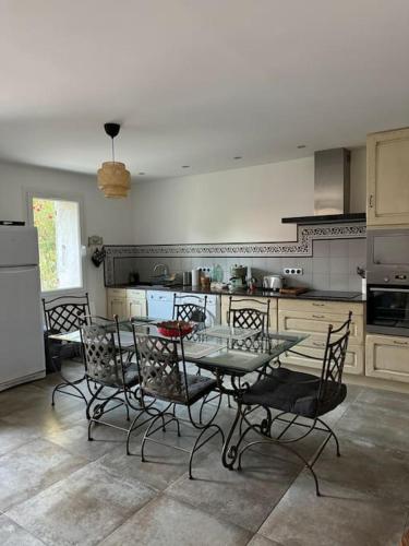 une cuisine avec une table en verre et des chaises. dans l'établissement Appartement bastide à la campagne, à Mimet