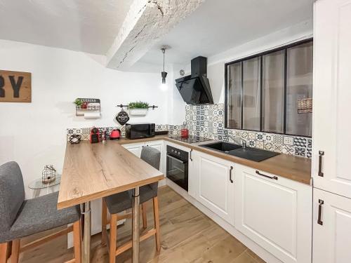 a kitchen with white cabinets and a wooden table at Loft cosy au cœur de Vence in Vence