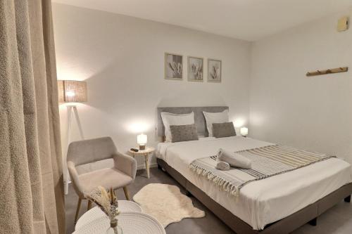 une chambre avec un grand lit et une chaise dans l'établissement Aux nuances de clairs - Studio cosy dans quartier historique cathédrale - Mon Groom, à Troyes