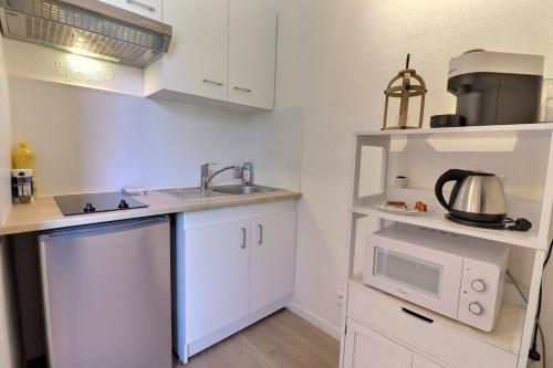 une petite cuisine avec un évier et un micro-ondes dans l'établissement Aux nuances de clairs - Studio cosy dans quartier historique cathédrale - Mon Groom, à Troyes