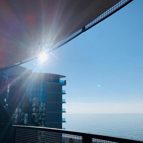 a building with the sun on top of it next to the ocean at Mgzavrebi Apartments in Kvariati