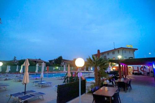 a resort with a pool and tables and umbrellas at Hotel Sporting in Casarsa della Delizia