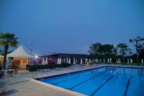 a swimming pool at night with chairs and umbrellas at Hotel Sporting in Casarsa della Delizia