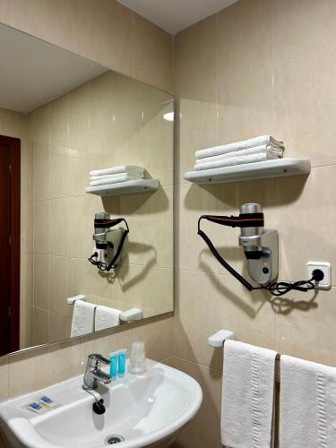 a bathroom with a sink and a mirror and towels at Pensión La Orozca Benidorm in Benidorm