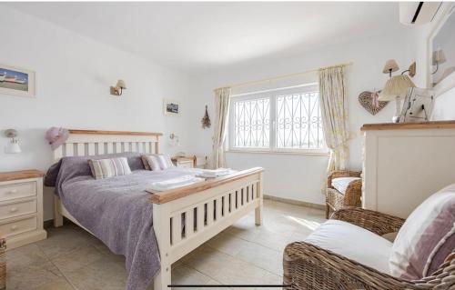 a bedroom with a bed and a chair and a window at Luxury 2 Bedroom Villa on Quinta da Saudade in Pêra