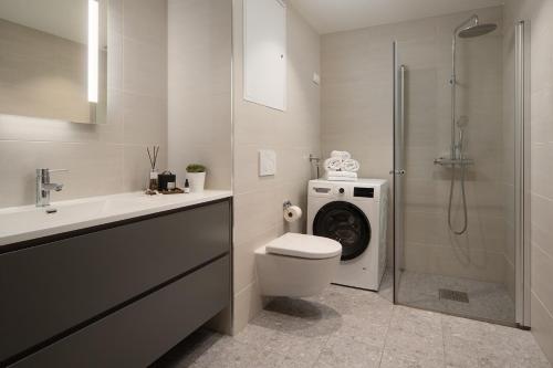 a bathroom with a toilet and a shower with a washing machine at BJØRVIKA APARTMENTS, Opera Area, Oslo city center in Oslo