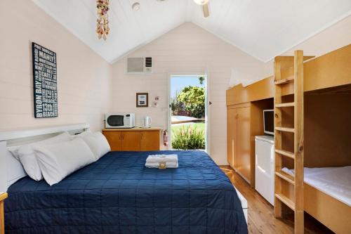 a bedroom with a bed and a kitchen with a window at Seven Mile Beach Holiday Park in Gerroa