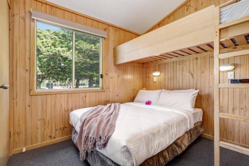 a bedroom with a bunk bed and a window at Seven Mile Beach Holiday Park in Gerroa