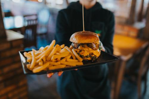 a person holding a plate with a sandwich and french fries at Harem House in Mielno