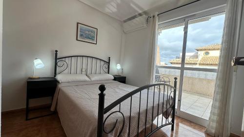 オリウエラにあるFamilienhaus in Cabo Roigのベッドと大きな窓のある寝室