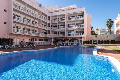 a swimming pool in front of a large building at Parque dos Reis, apartment 3 B in Monte Gordo
