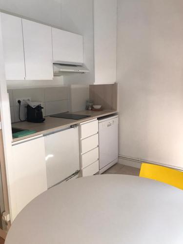 Elle comprend une petite cuisine avec des placards blancs et une chaise jaune. dans l'établissement Home & Home Metz Arènes, ctr congres, Muse, Pompidou, à Metz