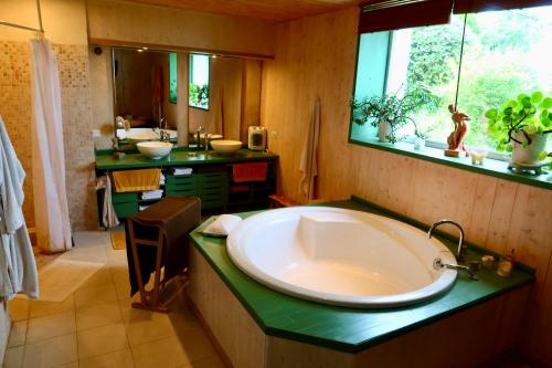 La salle de bains est pourvue d'une grande baignoire et d'un lavabo. dans l'établissement La Goronière - Superbe Charentaise rénovée - 2 logements - Piscine chauffée, à Saint-Laurent-de-la-Barrière