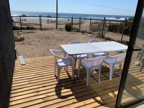 a table and chairs on a deck with the beach at Cabaña Azul Maitencillo in Valparaíso